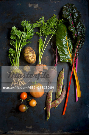 Various fresh vegetables on a dark surface (seen from above)