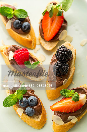 Baguette slices topped with nougat cream and berries as snacks for children