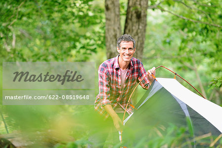 Caucasian man putting up a tent at a camp site