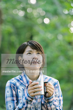 Young Japanese woman drinking coffee at a camp site