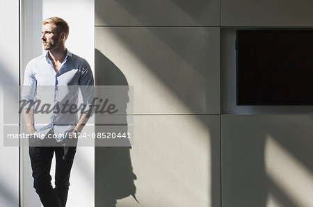 Businessman looking away at sunny window