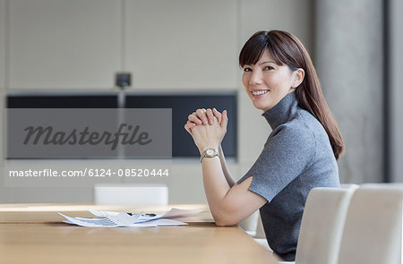 Portrait confident businesswoman with paperwork in conference room
