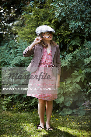 Portrait of girl looking through magnifying glass