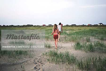 Mother with daughter walking on sand dune