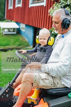 Grandfather with grandson on ride-on lawn mower