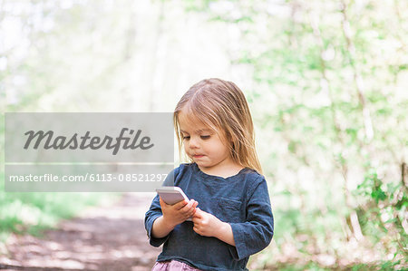 Toddler girl using cell phone in park