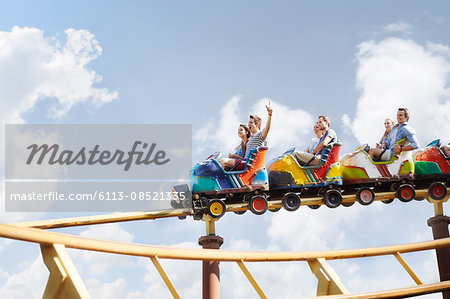 Friends cheering riding roller coaster at amusement park