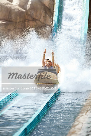 Enthusiastic young man riding water log amusement park ride