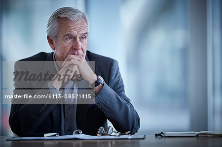 Pensive senior businessman looking away in conference room