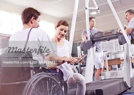 Physical therapist showing digital tablet to man in wheelchair