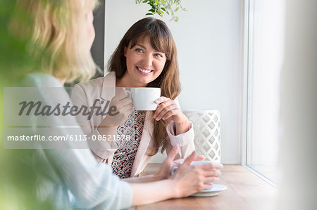 Smiling women drinking coffee at cafe window