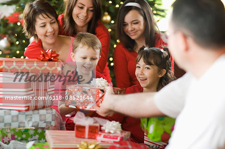 A group of people, parents and children, family exchanging presents on Christmas morning.