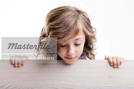 little girl watches down from behind a wooden table