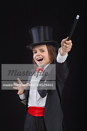 Happy young magician performing a trick with wide gestures - on dark background