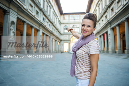 Be inspired by Uffizi Gallery. Young woman tourist pointing on Uffizi Gallery in Florence, Italy