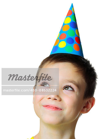 Portrait of eight years boy with birthday cap looking up on white background