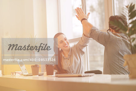 Toned Happy smiling freelance man and woman doing high-five in office. Business people or students working in library with laptop computers.