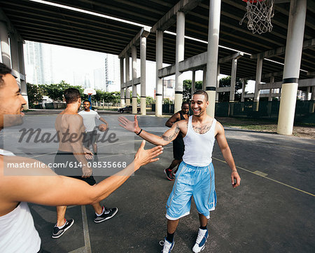Young men on basketball court connecting with handshake after basketball game smiling