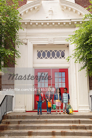 Portrait of four boys and girls standing elementary school entrance