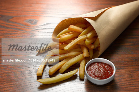 High angle view of chips in paper cone with bowl of tomato ketchup