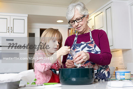 Girl and grandmother measuring salt for cooking