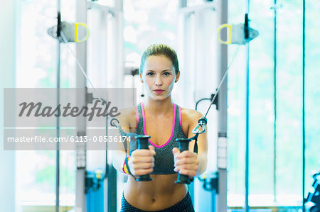 Focused woman using cable exercise equipment at gym