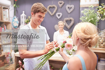 Florist tying flowers for woman in flower shop