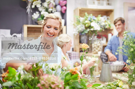 Smiling florist arranging bouquet in flower shop