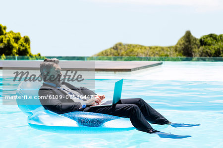 Businessman using laptop on inflatable