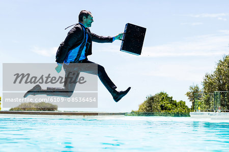Businessman jumping in the swimming pool