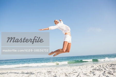 Blonde woman jumping on the beach