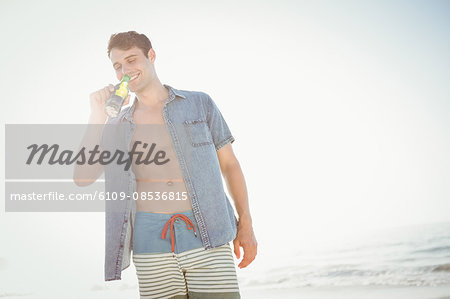 Smiling man drinking beer on the beach