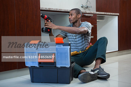 Manual worker drilling a hole in kitchen