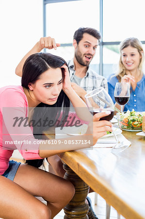 Friends looking drunk woman with wine glass