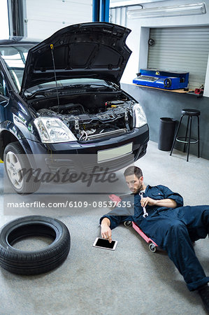 Mechanic using digital tablet while repairing a car