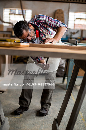 Carpenter working on wooden plank in workbench