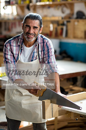 Carpenter cutting plank with hand saw