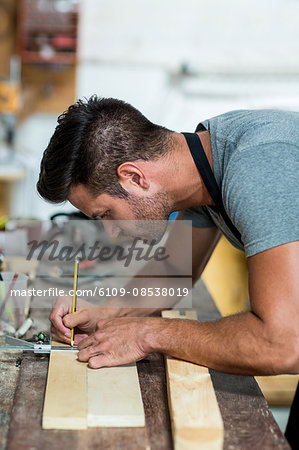 Carpenter marking on wooden plank with pencil