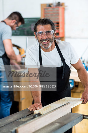 Carpenter using table saw for cutting wood at workbench