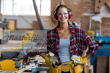 Portrait of female carpenter standing with hand on hip