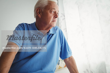 Thoughtful senior man sitting on his bed