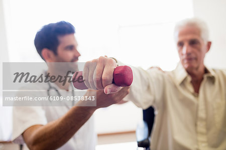 Nurse helping senior man with doing exercises