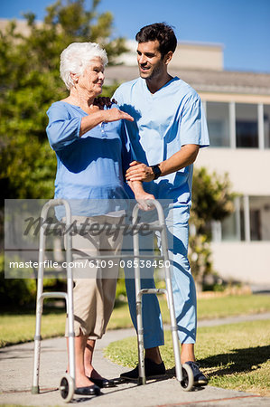 Nurse pushing the senior womans Zimmer frame Nurse pushing the senior womans Zimmer frame