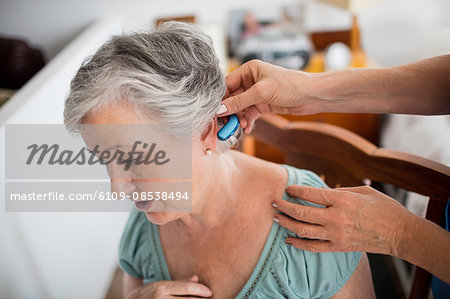 Nurse putting hearing aid to a senior woman