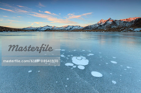 Ice bubbles on the frozen surface of Andossi Lake at sunrise, Spluga Valley, Valtellina, Lombardy, Italy, Europe