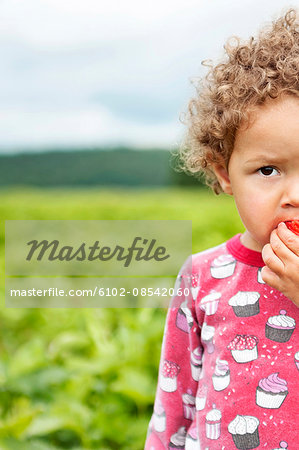 Small girl eating strawberry