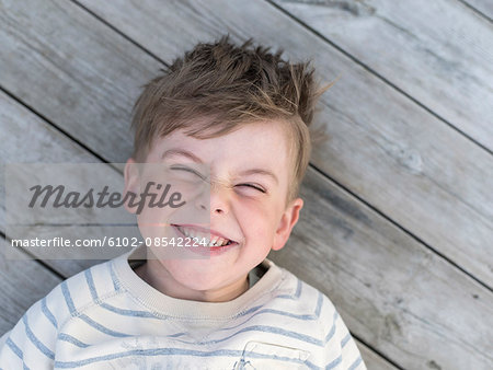 Portrait of smiling boy lying on boardwalk