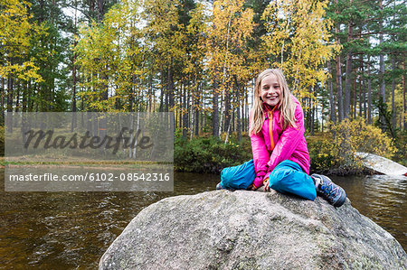 Girl sitting on rock in lake