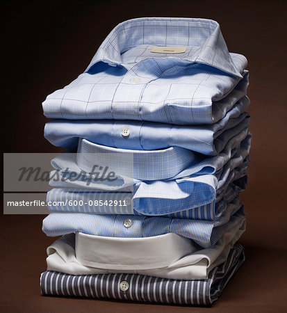 Stack of men's dress shirts on brown background