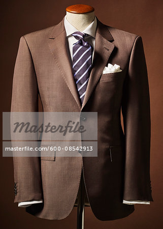 Brown suit jacket on bust with handkerchief and tie on brown background